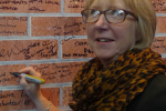 Maggie signs the social action wall